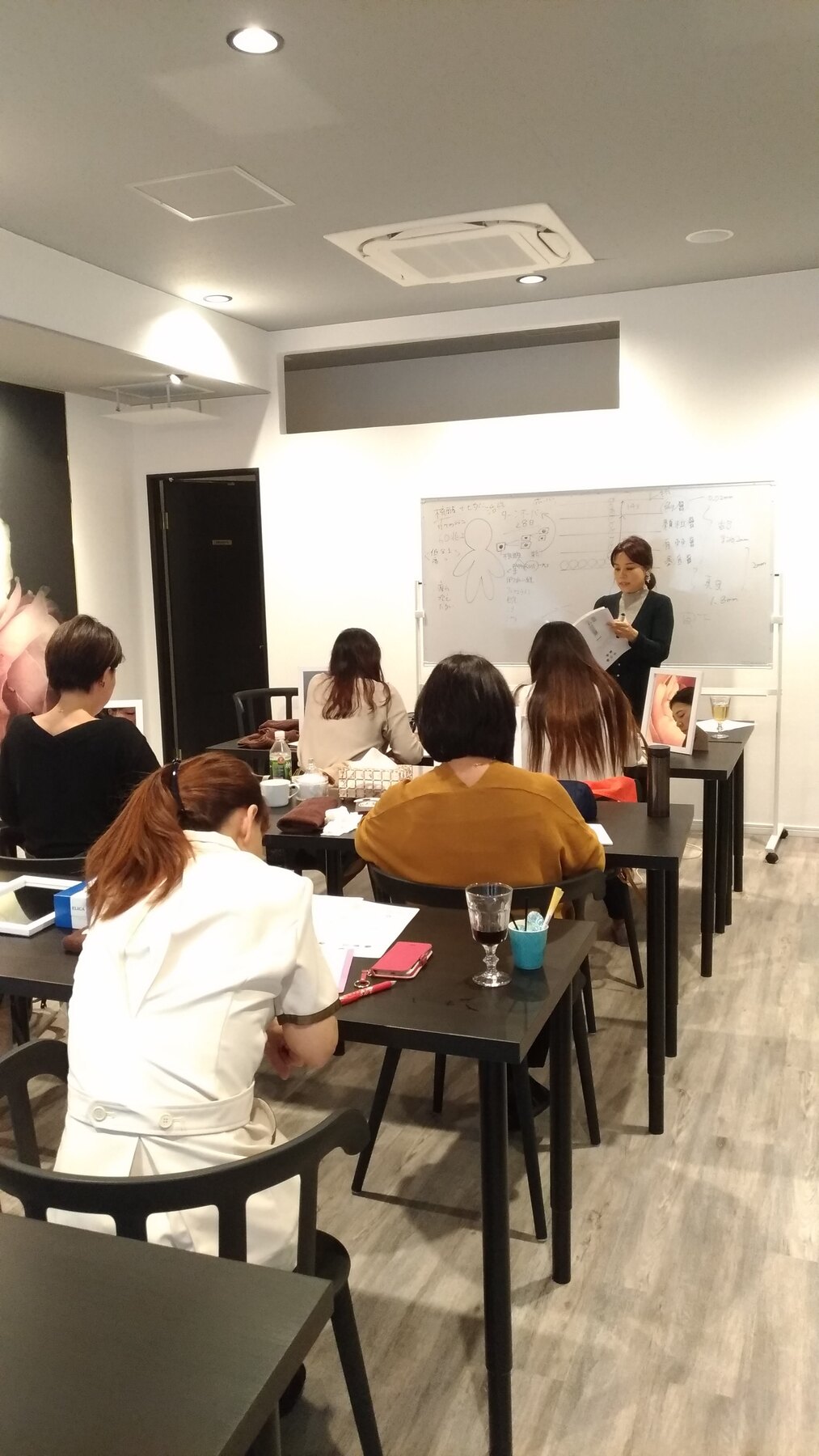 講師がホワイトボードで説明し、受講者がノートを取りながら学ぶ研修風景